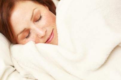 A woman sleeping soundly under a white blanket